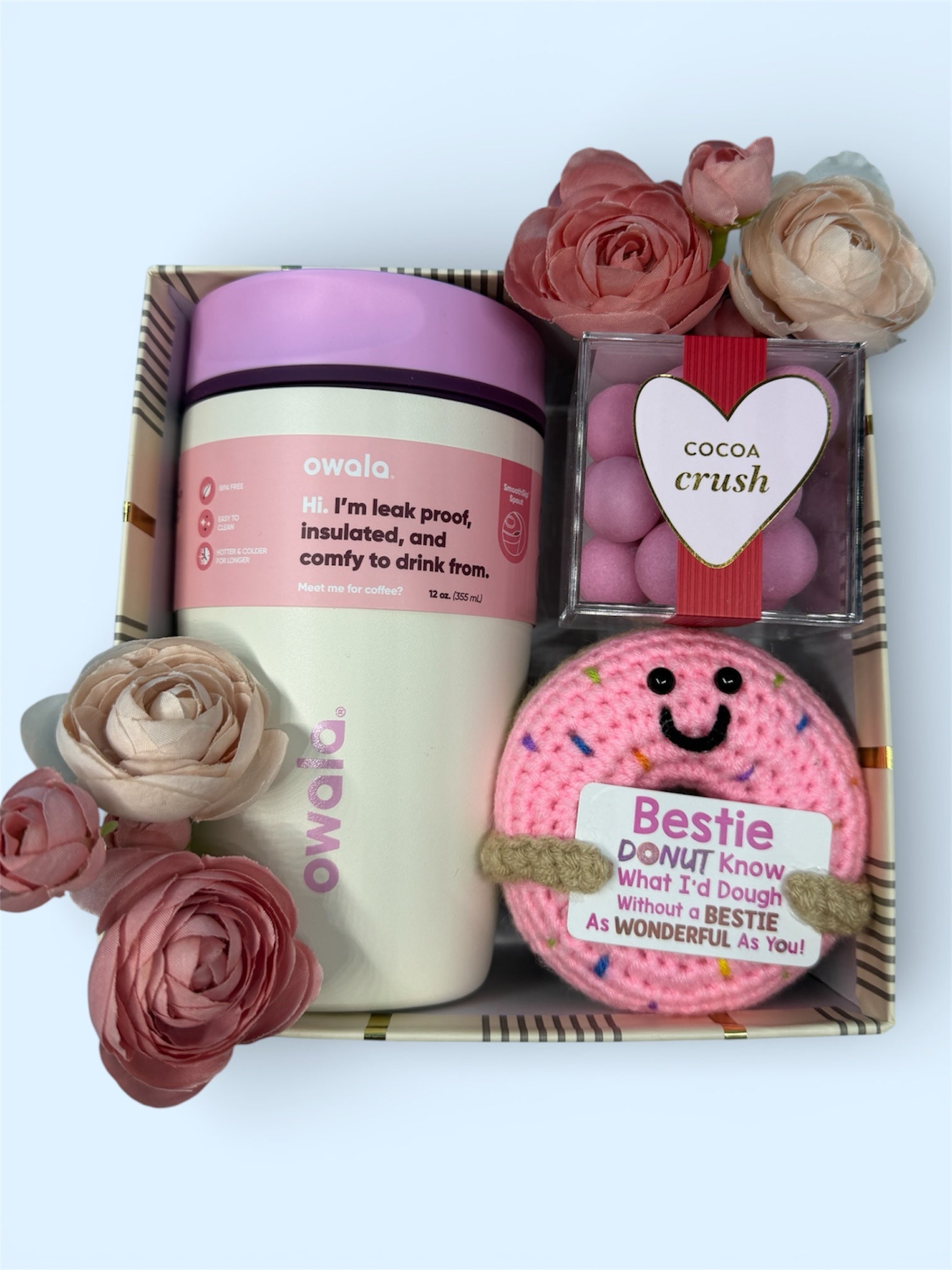 Gift set with a pink and white Owala cup, a pink handmade crochet donut with a note for a friend, and a Shugarfina Candy cube. Decorated with flowers.