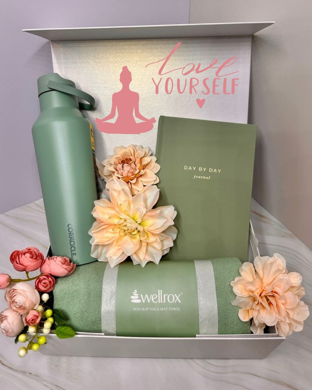Wellness gift set with water bottle, yoga anti-grip towel, and journal. Bow decorated with flowers and personalized with a note on the lid. 